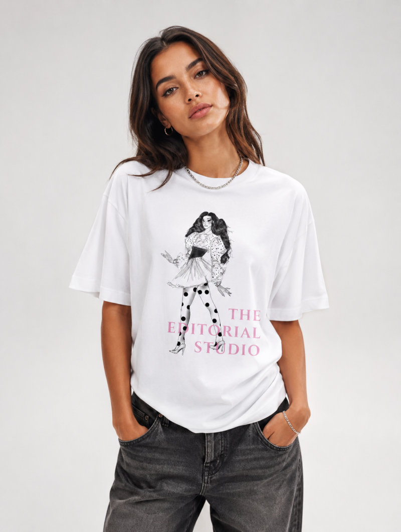 Mannequin femme portant un t-shirt oversize blanc imprimé avec l'illustration 'Mona Lisa Polka Dotted Girl' et le logo rose 'THE EDITORIAL STUDIO'. Tenue avec pantalon large noir et sac à main.